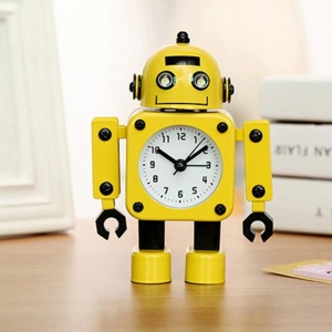 Alarmuhr in Form eines gelben Roboters auf braunem Möbelstück mit Büchern