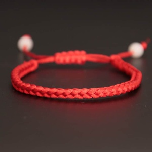 Armband aus handgeflochtenem rotem Seil auf schwarzem Hintergrund