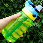 Auslaufsichere 480-ml-Flasche mit Deckel und Strohhalm in grün, gelb und blau vor einem Baum