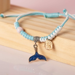 Geflochtenes Armband mit Meerestieranhänger in blau und weiß auf einem Holzregal
