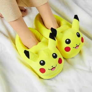Babyschuhe in Form von Pikachu aus Plüsch, auf die Füße gesteckt, mit einer weißen Decke