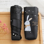 Mini Taschenschirm für Kinder mit weißem Kaninchen auf schwarzem Regenschirm auf einem Holztisch