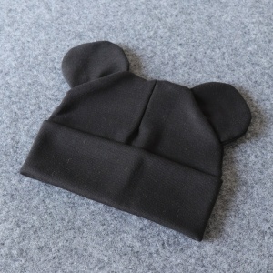 Baumwollmütze mit kleinen Ohren für Babys in Schwarz auf grauem Hintergrund