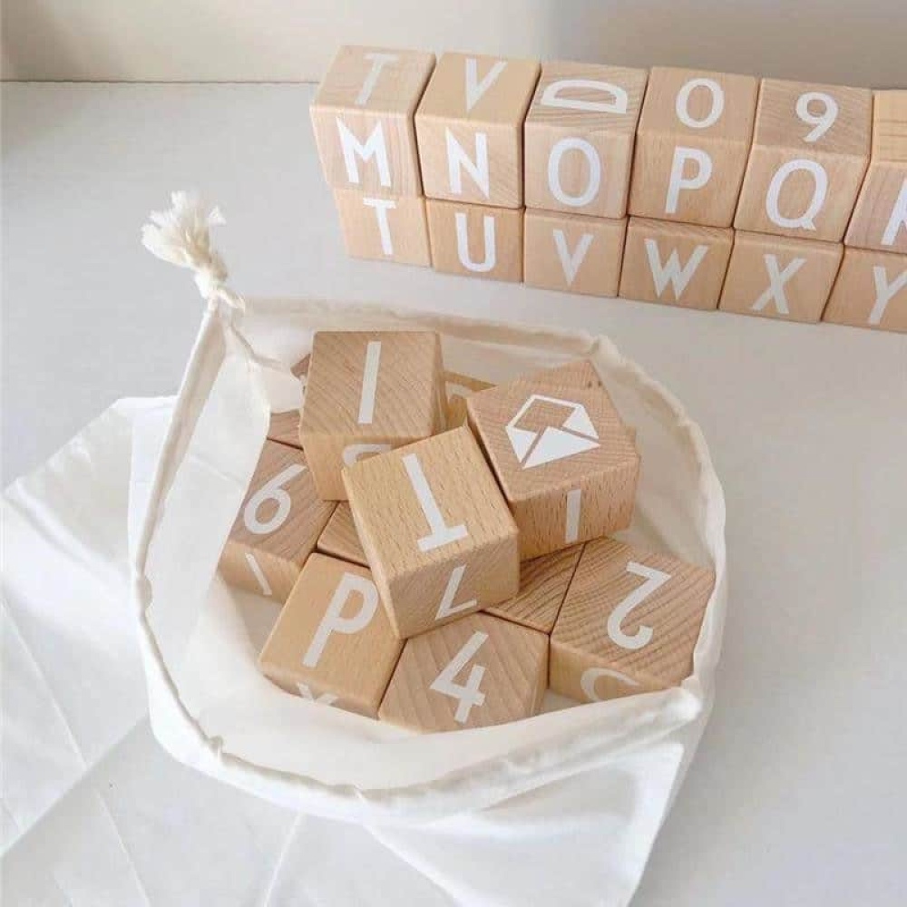 Alphabet-Spielzeug aus Holz zum Stapeln in einer weißen Tasche auf einem weißen Tisch