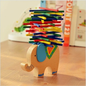 Spiel mit Balancierblöcken für Kinder mit einem hölzernen Elefanten mit blauen Ohren auf einem Holztisch