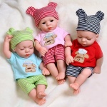 Wasserdichte Puppe für Neugeborene mit rosa, roten, grünen und blauen Kleidungsstücken auf einem weißen Mantel