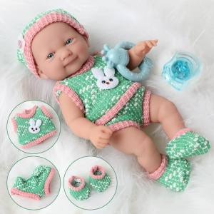 Weiche Puppe für Neugeborene mit Kleidung in grün und rosa auf einem weißen Mantel