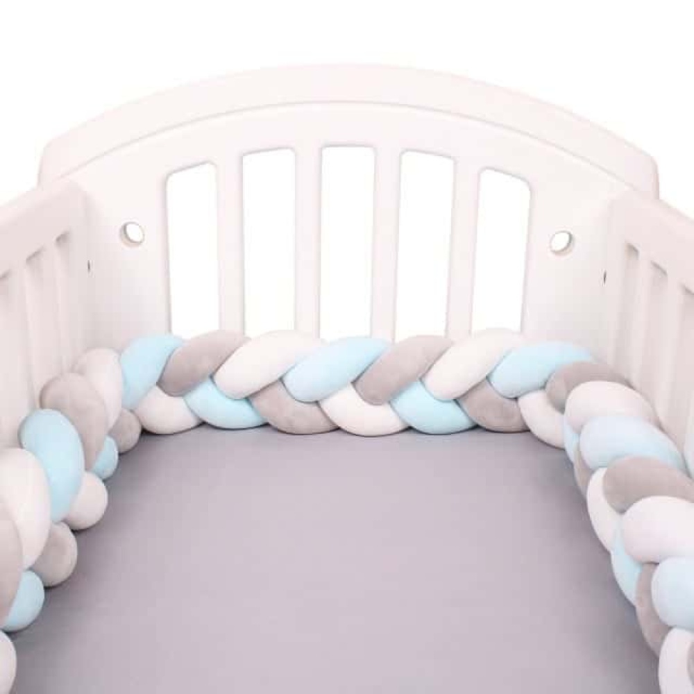 Geflochtener Bettumrandung weiß grau blau in einem weißen Babybett mit grauer Bettwäsche