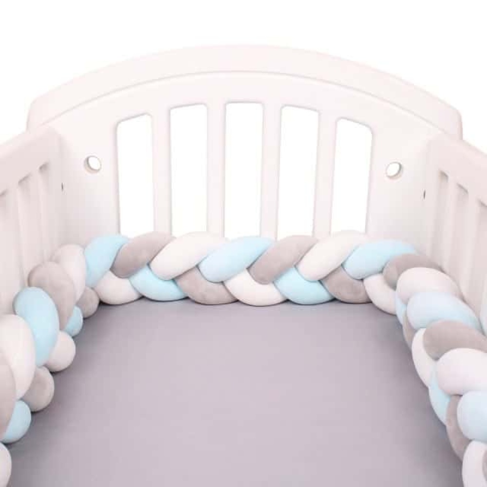 Bettumrandung aus Flechtstoff weiß grau blau Geflochtener Bettumrandung weiß grau blau in einem weißen Babybett mit grauer Bettwäsche