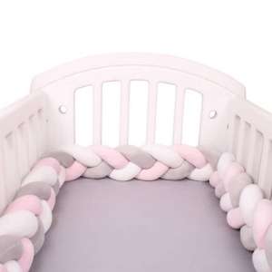 Geflochtener Bettumrandung in rosa, weiß, grau in einem weißen Babybett mit grauer Bettwäsche