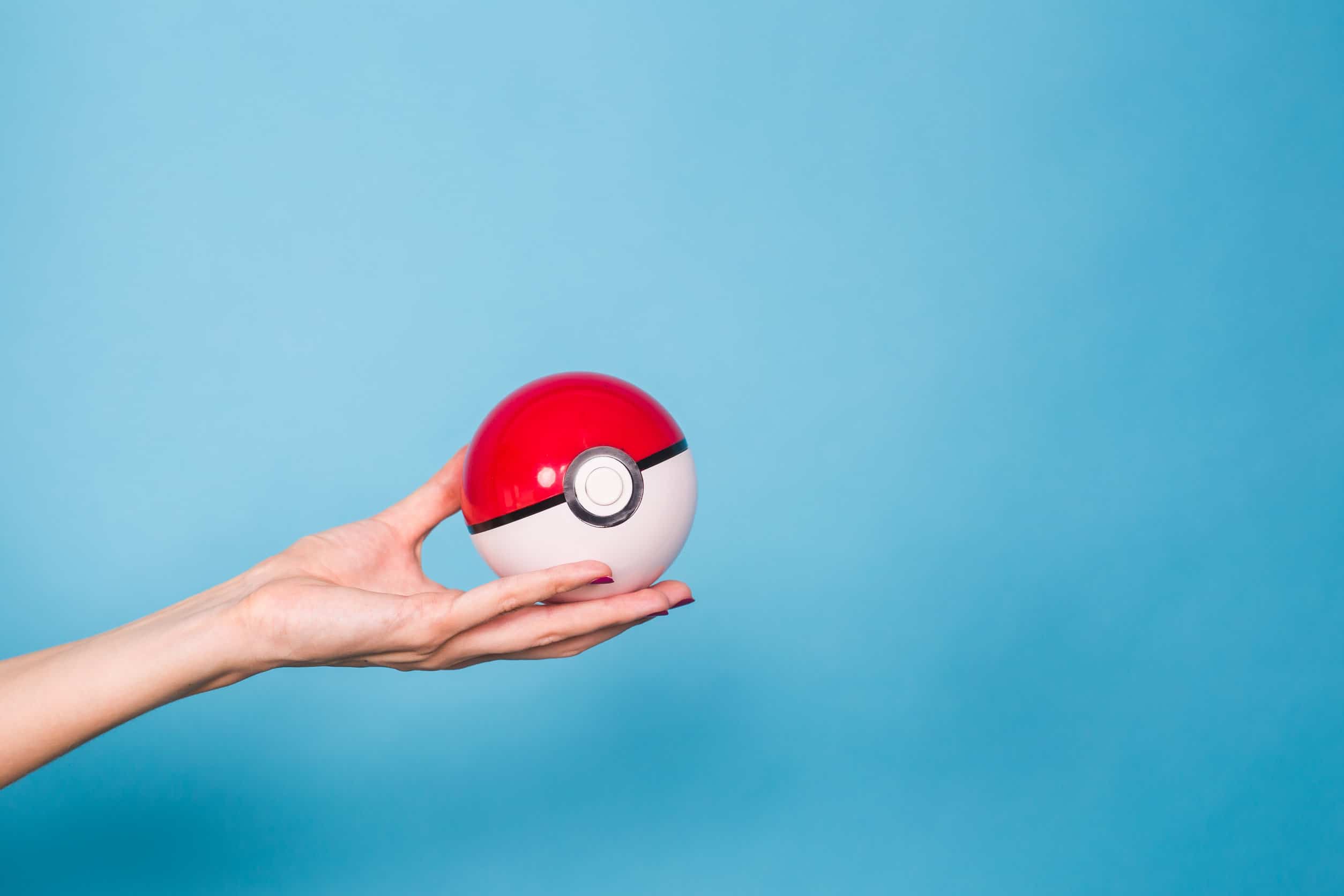 Eine Hand mit einem rot-weißen Pokémon-Pokeball auf blauem Hintergrund