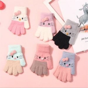 Niedliche und warme gestrickte Winterhandschuhe für Kinder mit niedlichem Katzenmotiv vorne auf einem rosa Hintergrund mit einem Buch