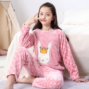 Ein Mädchen, das den Polarpyjama mit einem weiß gepunkteten Kaninchenmuster in ein Bett trägt