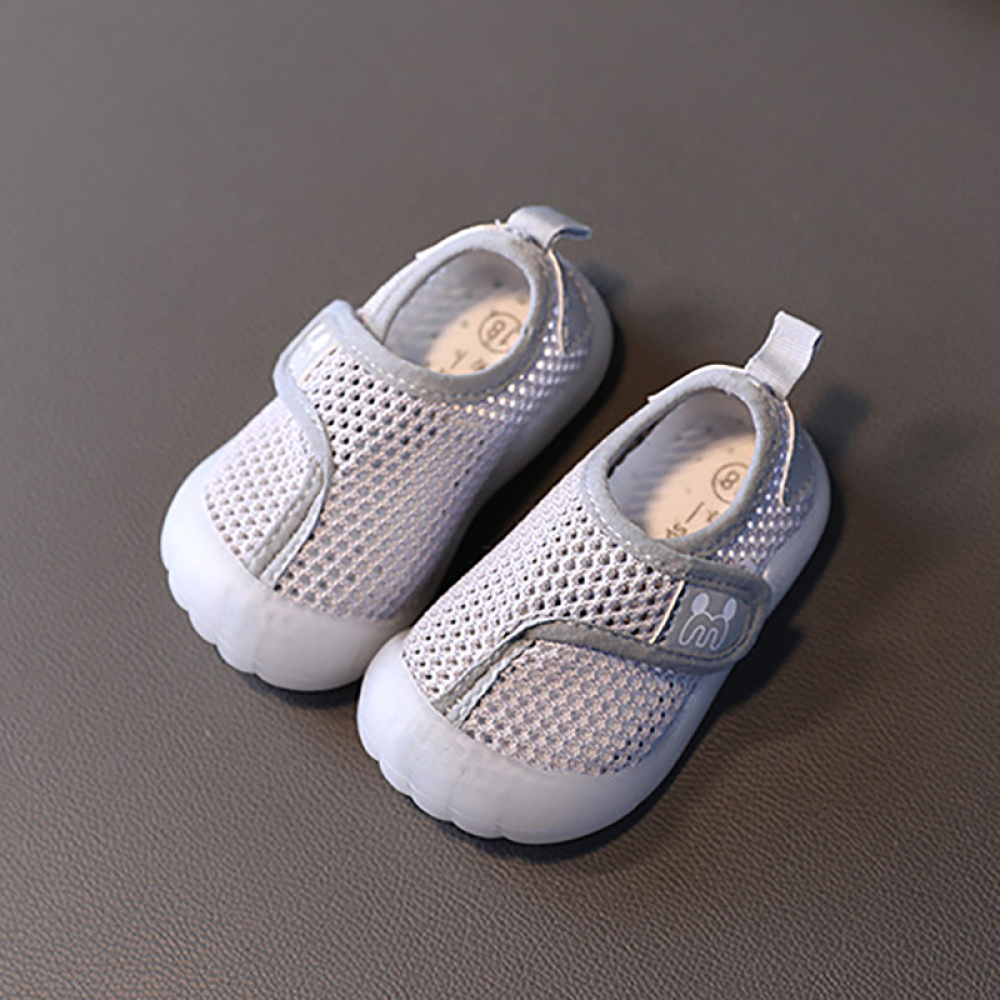 Strandschuhe für Kinder aus grauem Mesh mit einer weißen Gummisohle. Sie stehen auf einem dunkelgrauen Hintergrund.