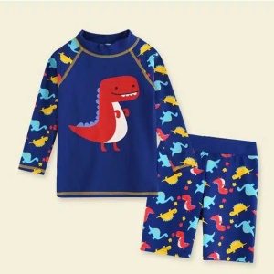 ein Kinderbadeanzugset aus blauen Shorts und T-Shirt mit Dinosauriermotiv auf beigem Hintergrund