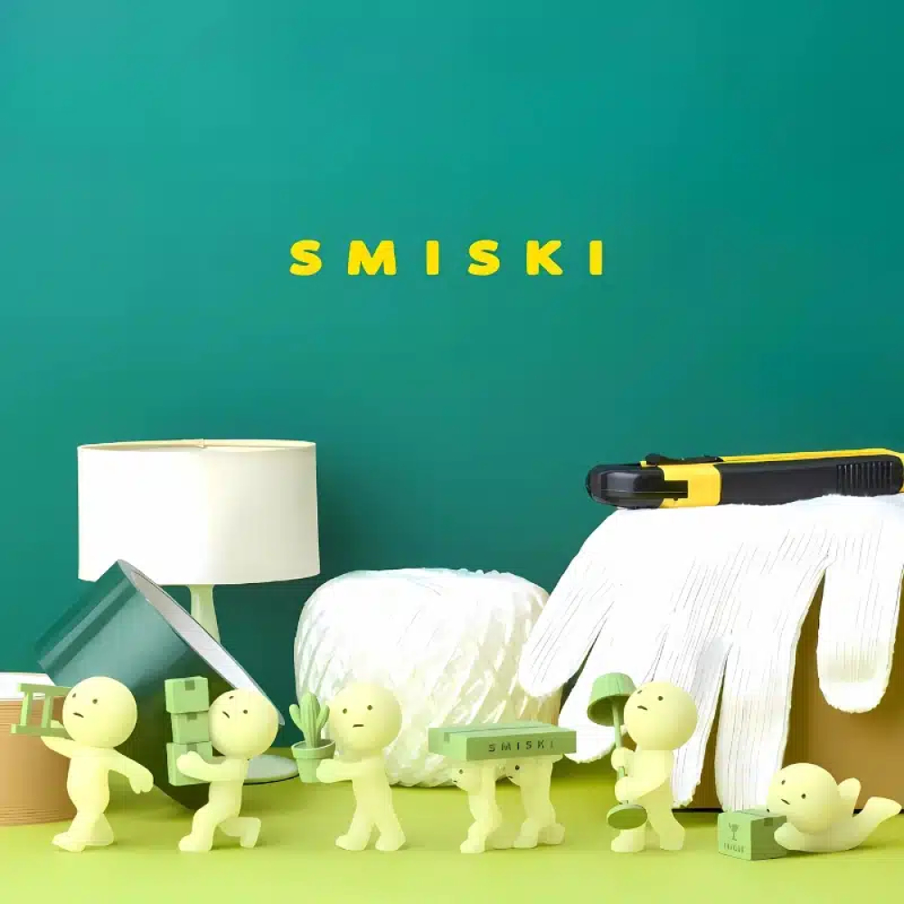 IMG_11_24_collection_smiski_moving_4.jpg Figurines Smiski collection Moving, mettant en scène de petites figurines phosphorescentes effectuant des tâches de déménagement, avec des cartons, des plantes et divers objets.
