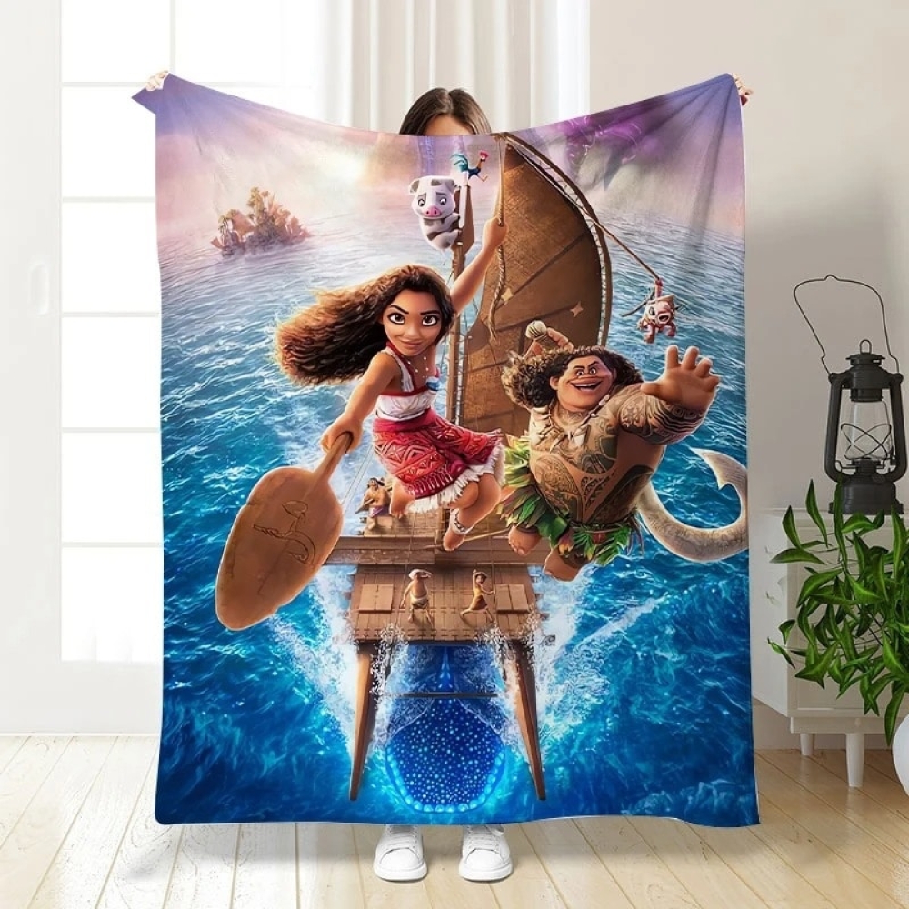 Image d'un plaid tout doux à l'effigie du film Disney Vaiana 2 . Il y a Vaiana et Maui sur une pirogue en pleine aventure sur l'océan, avec des couleurs vives et un décor tropical.