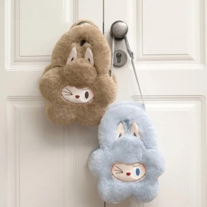 Zwei kleine, weiche Handtaschen in Blumenform mit Labubu-Gesicht, das zwinkert, und großen Hasenohren; eine himmelblau, die andere hellbraun. Sie hängen an einem Türgriff.