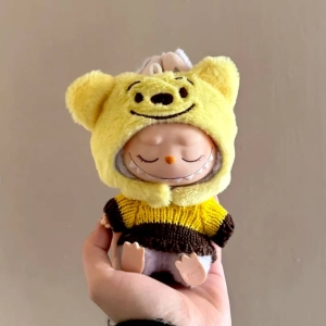 Kleidungsset für Plüschtier mit gelber Kapuze mit lachenden Ohren und gelb-braun gestreiftem Pulli, getragen von einer schlafenden Labubu-Figur.